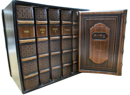 A decorative leather-bound Hebrew mezuzah case or decorative book set displayed open on a light wood surface. The set includes multiple dark brown textured spines with gold lettering and a matching ornate wooden front cover with Hebrew text.